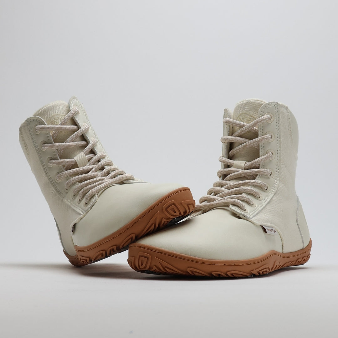 Off white barefoot winter boot with the sole leaning against the toe box on a light gray background.
