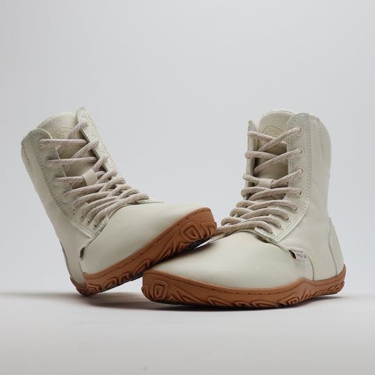 Off white barefoot winter boot with the sole leaning against the toe box on a light gray background.