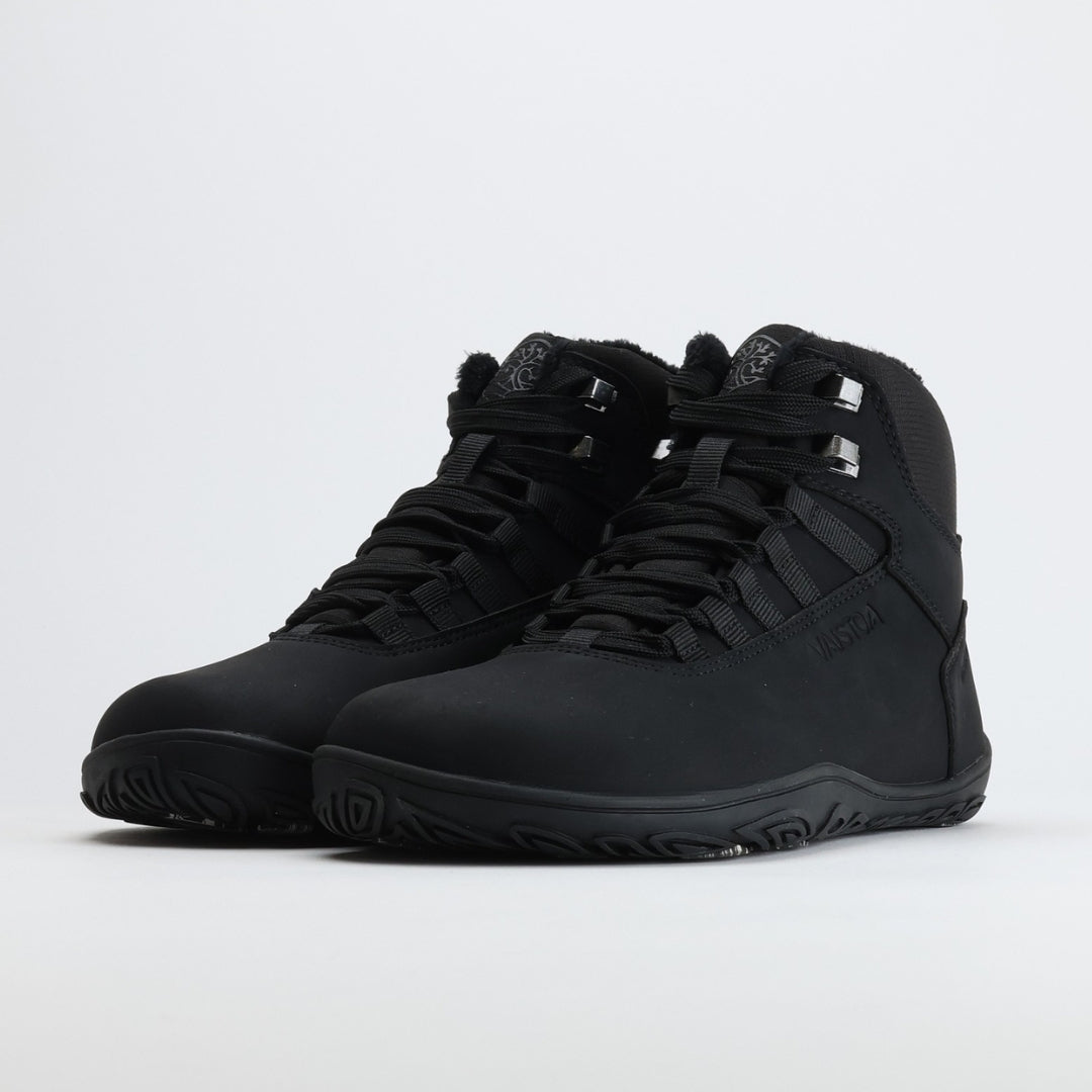 Pair of black high-top barefoot hiking boots shown from a front angle on a light gray background.