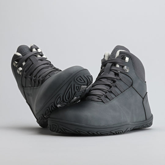 Frost gray barefoot hiking boot with the sole leaning against the toe box on a light gray background.