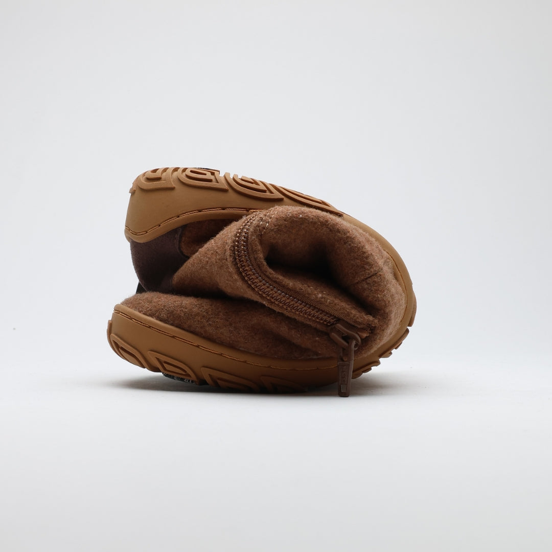 Roasted almond barefoot winter felt Chelsea boot folded to demonstrate its thin and flexible sole on a light gray background.
