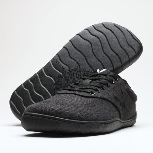 Vaistoa Huoleton barefoot hemp sneakers – soft black, studio shot of the pair, one shoe on its side showing the wave pattern of the Vaistoa Aalto outsole and the other standing sideways in front, light background