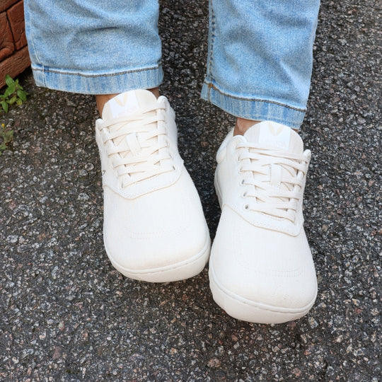 Vaistoa Huoleton barefoot hemp sneakers – natural hemp, shoes worn on asphalt photographed from above with blue jeans, both shoes visible