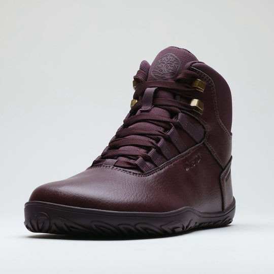 Vaistoa Uoma 2 barefoot trekking boots plum red – a single boot seen from a front three-quarter angle, with the ankle-high shaft, the lacing, the brass-coloured speed hooks and the tree emblem embossed on the tongue visible