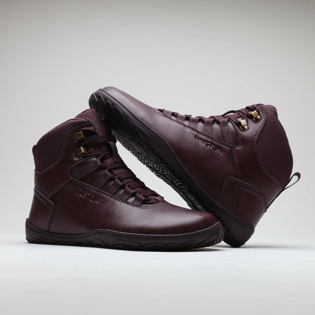 Vaistoa Uoma 2 barefoot trekking boots plum red – one boot standing and the other lying on its side resting against it, so that the outsole of the fallen boot is visible at an angle