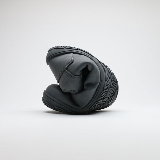 Pakkasharmaa Vaistoa Uoma Talvi 3 -kenkä rullattuna kokoon taipuisuuden havainnollistamiseksi. Kuvassa näkyy ohut ja joustava talvipohja.