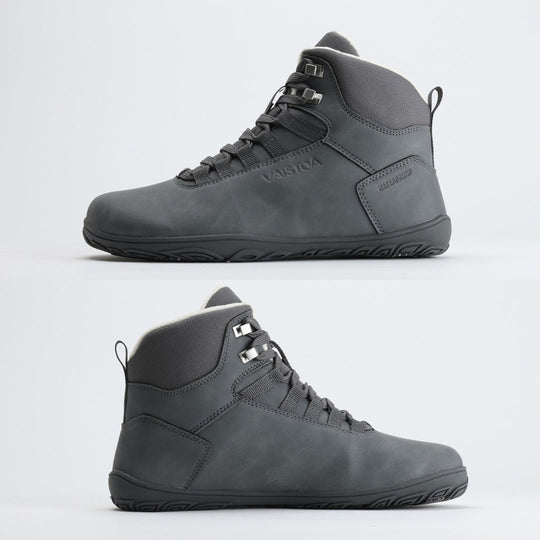 Kaksi pakkasharmaata Vaistoa Uoma Talvi 3 -kenkää kuvattuna sivusta, mediaali- ja lateraalipuolelta. Kuvassa korostuu kengän tasainen zero drop -pohja ja vedenpitävä rakenne.