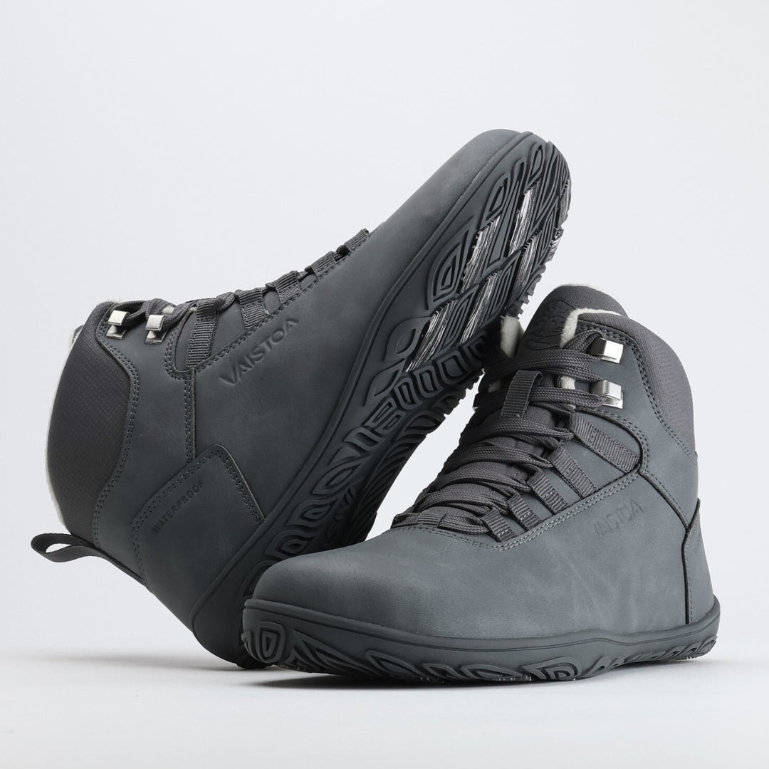 Frost gray barefoot hiking boot with the sole resting against the upper, showing visible grip zones on the winter sole.