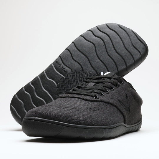 Vaistoa Huoleton barefoot hemp sneakers – soft black, studio shot of the pair, one shoe on its side showing the wave pattern of the Vaistoa Aalto outsole and the other standing sideways in front, light background
