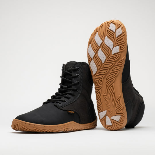 Vaistoa Hurmos 3 casual winter barefoot boots – pair with one shoe standing and the other leaning upright against its shaft with the outsole facing the camera, showing the Vaistoa logo and grip pads