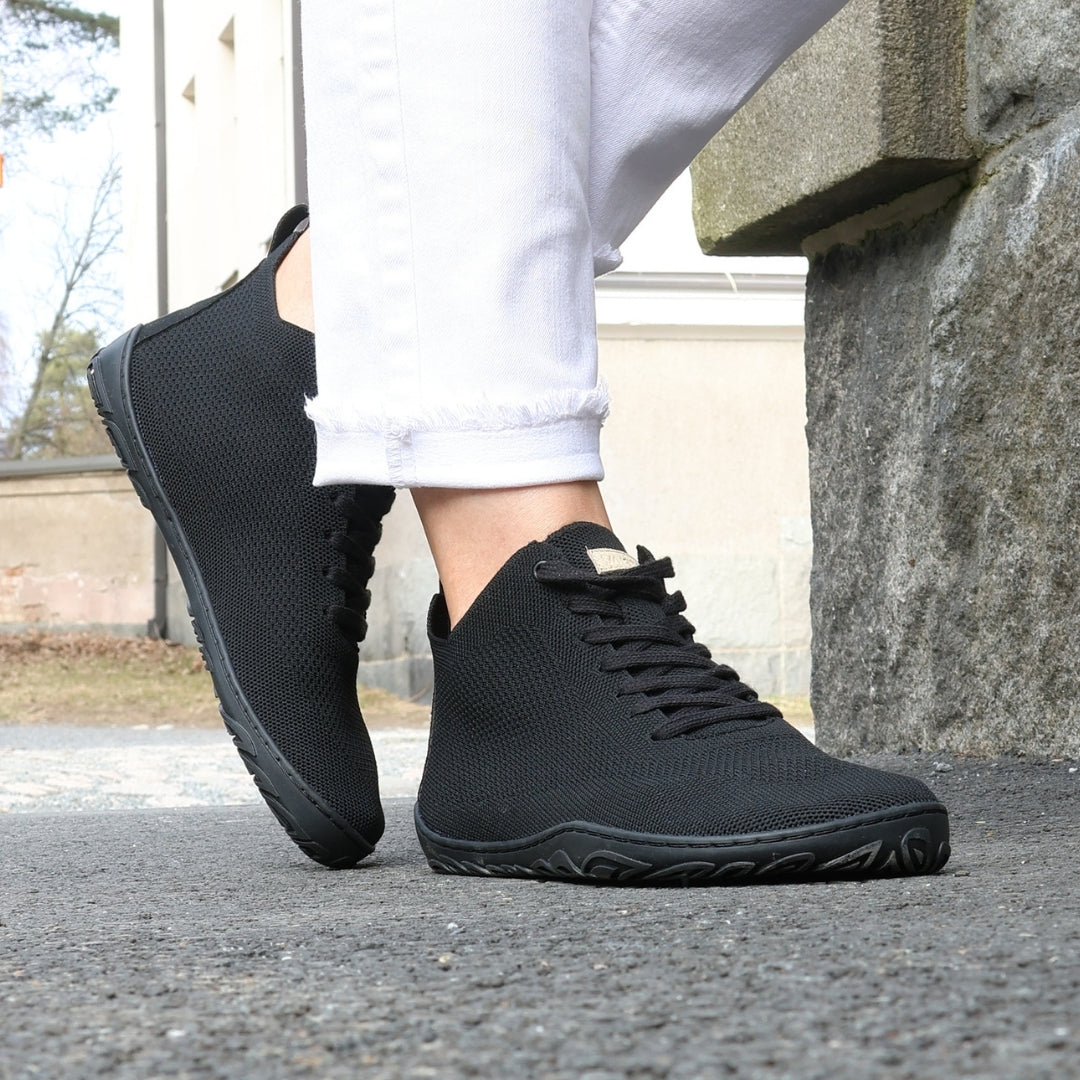 vaistoa iloa mid barefoot shoes knitted high top sneakers black lifestyle spring step on asphalt grey stone wall