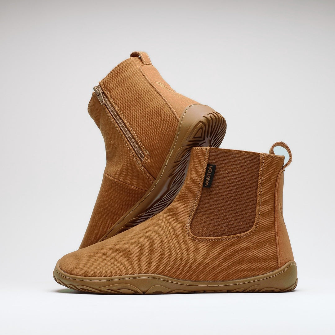 Vaistoa Kajo 2 barefoot chelsea boots – almond brown pair with one shoe on its side showing the zipper and the other standing in front showing the elastic panel against a light background