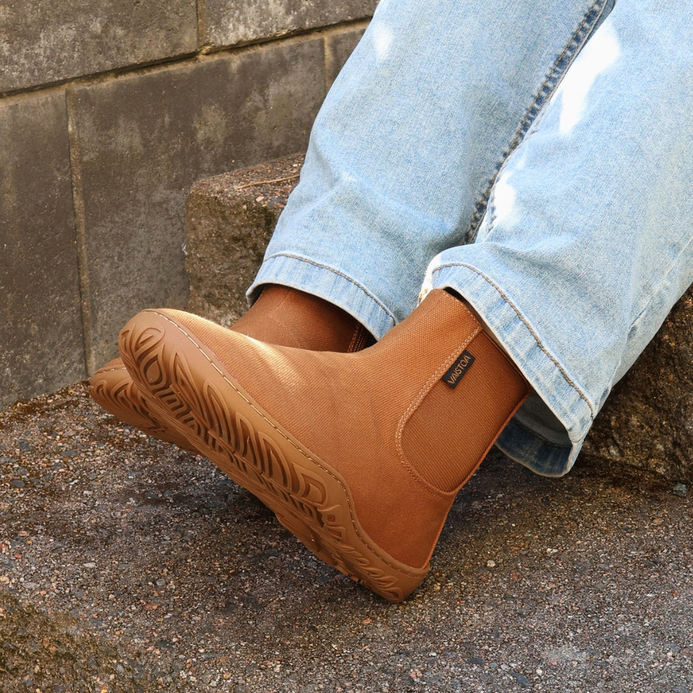 Vaistoa Kajo 2 barefoot chelsea boots – almond brown shoes worn on foot, person sitting on stone steps with legs crossed, light jeans