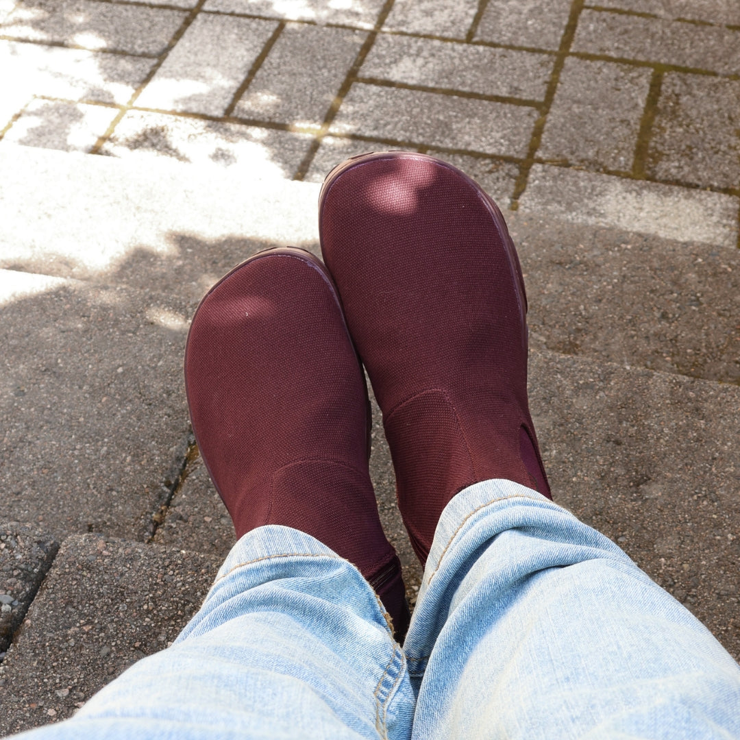 Vaistoa Kajo 2 barefoot chelsea boots – burgundy shoes worn on foot on paving, shown from above, light jeans