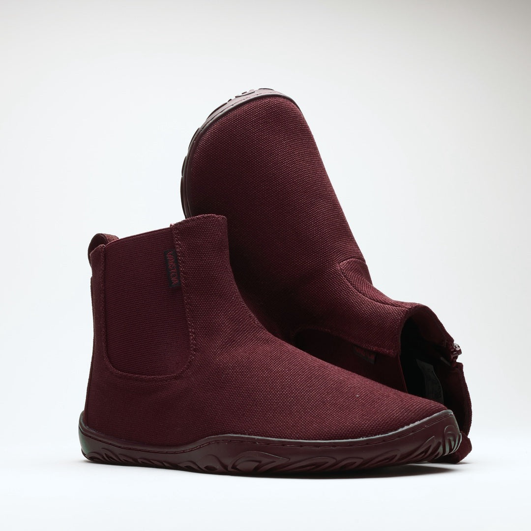 Vaistoa Kajo 2 barefoot chelsea boots – burgundy pair with one shoe resting on the other so the side zipper and the edge of the outsole are visible against a light background