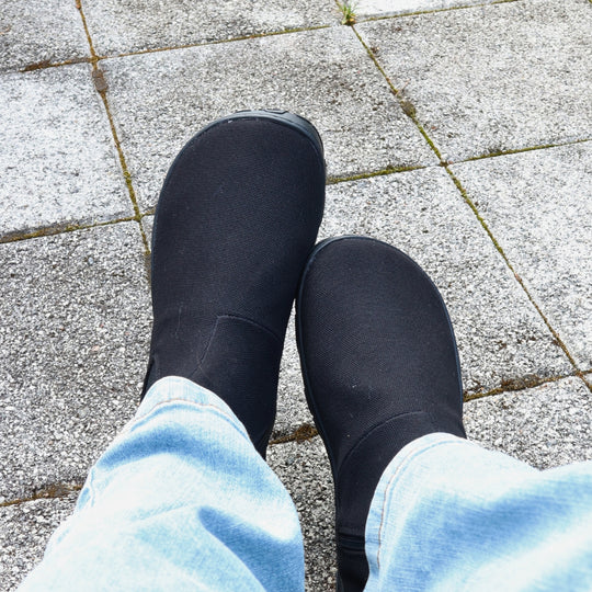 Vaistoa Kajo 2 barefoot chelsea boots – classic black shoes worn on foot on paving, shown from above, light jeans