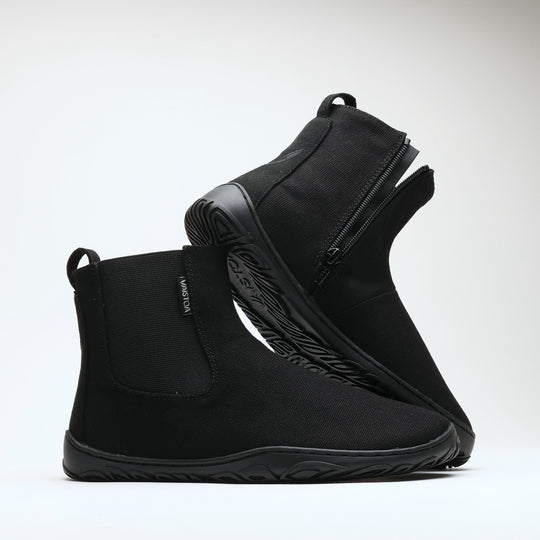 Vaistoa Kajo 2 barefoot chelsea boots – classic black pair with one shoe resting on the other so the side zipper and the edge of the outsole are visible against a light background