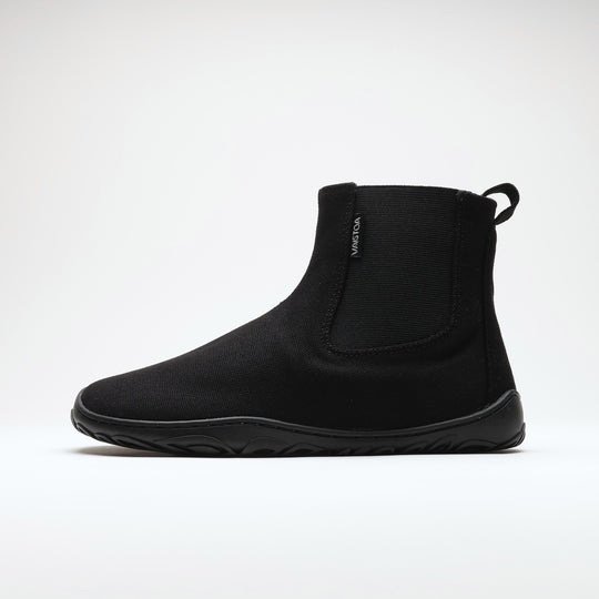 Vaistoa Kajo 2 barefoot chelsea boots – classic black shoe shown from the side with the elastic panel visible, flat zero-drop sole against a light background