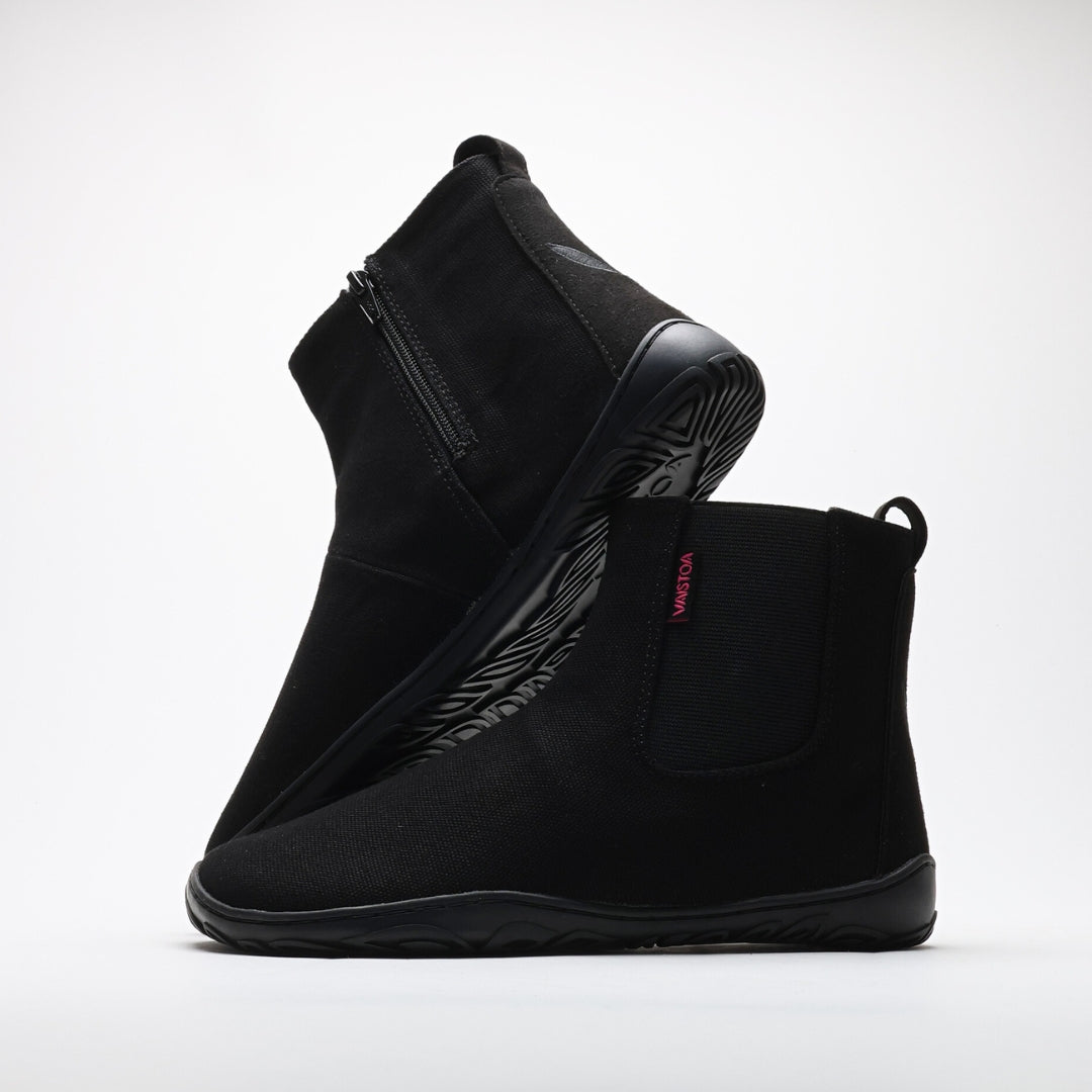 Vaistoa Kajo barefoot Chelsea boots – black, studio shot of the pair, the back boot tilted so the outsole shows and the front boot side-on with the elastic panel and heel loop visible, light background