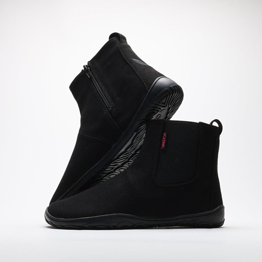 Vaistoa Kajo barefoot Chelsea boots – black, studio shot of the pair, the back boot tilted so the outsole shows and the front boot side-on with the elastic panel and heel loop visible, light background
