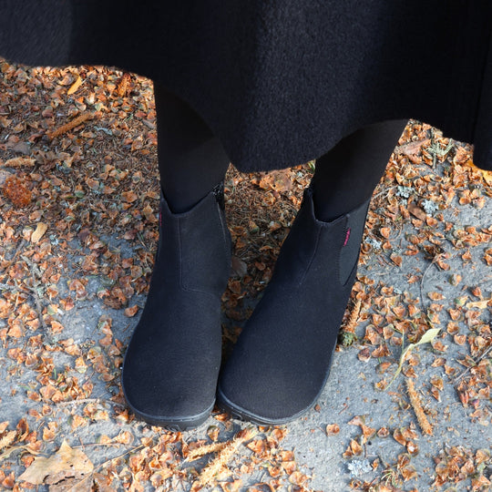 Vaistoa Kajo barefoot Chelsea boots – black, boots worn on autumn leaves with a dark coat, both boots seen from the front
