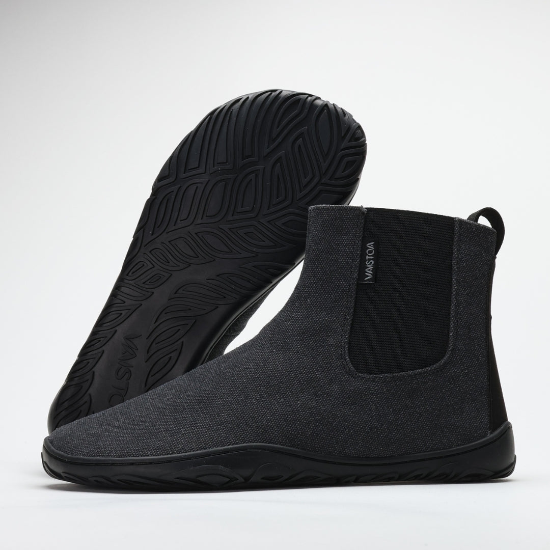 Vaistoa Kajo barefoot Chelsea boots – smoky stonewashed grey, studio shot of the pair, one boot tilted with the leaf-patterned outsole towards the camera and the other standing beside it