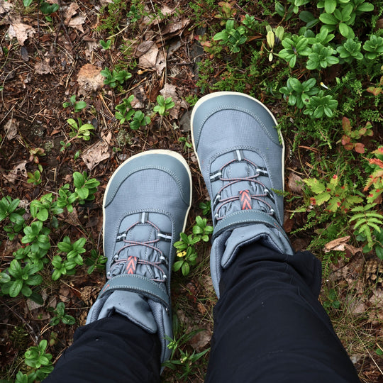 Vaistoa Kaste waterproof barefoot shoes for kids blue grey – worn shoes seen from directly above on the forest floor, surrounded by lingonberry sprigs and moss