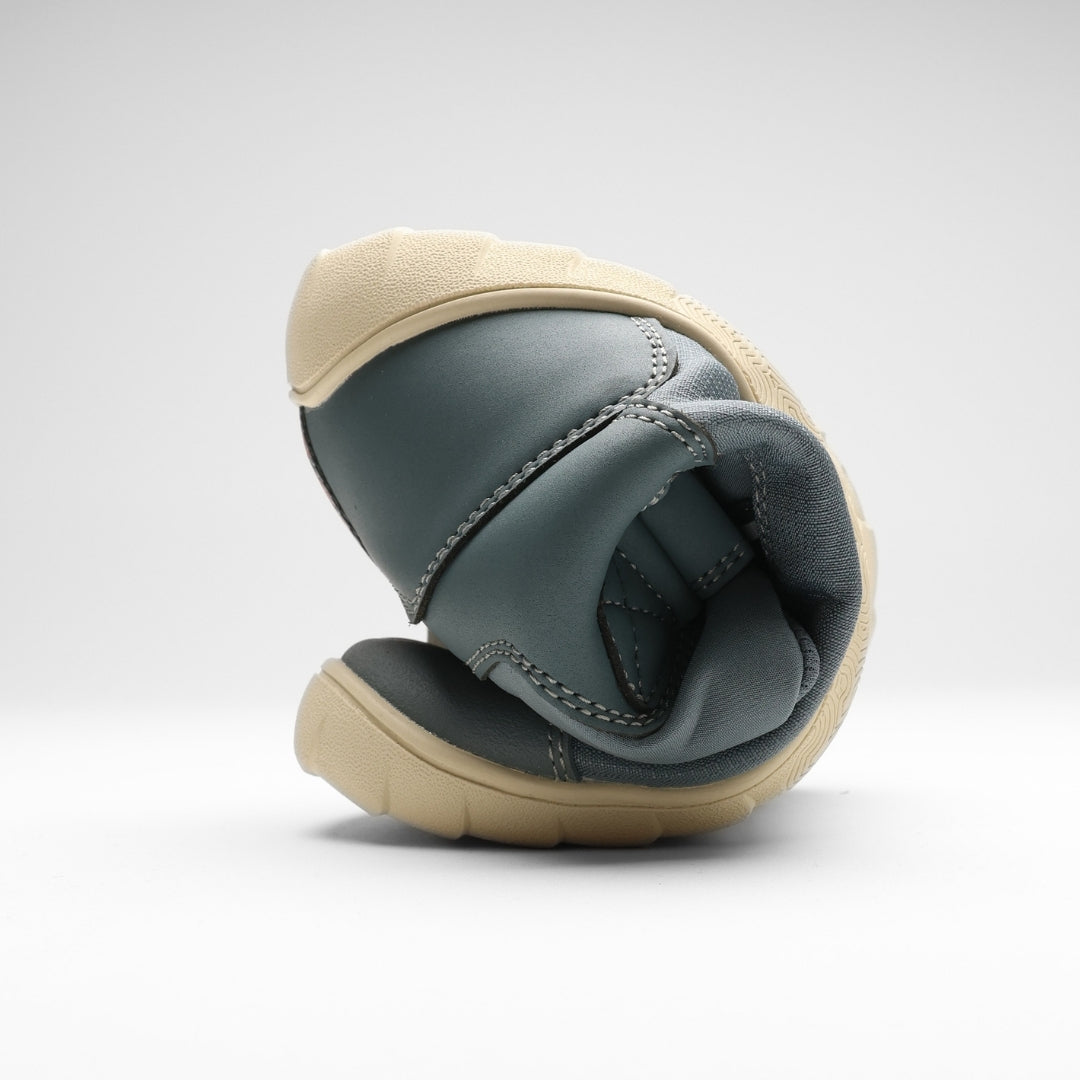 Vaistoa Kaste waterproof barefoot shoes for kids blue grey – one shoe rolled up so that the toe and the heel meet, showing how flexible the outsole is