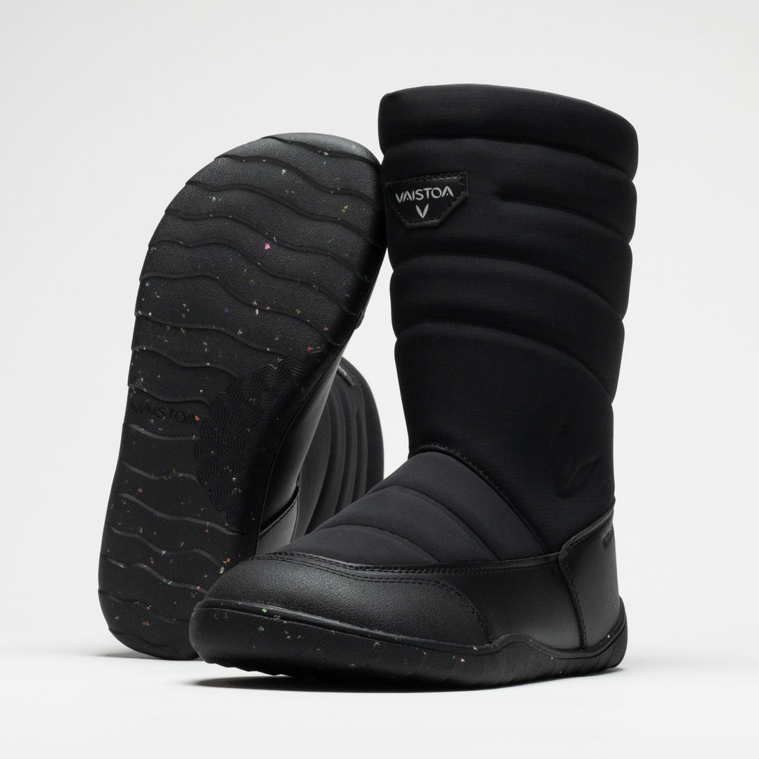 Vaistoa Kinos 2 kids' barefoot winter snow boots, colour Quilted black – studio photo: pair, one boot leaning against the other's shaft with the sole facing the camera, Vaistoa logo on the shaft.