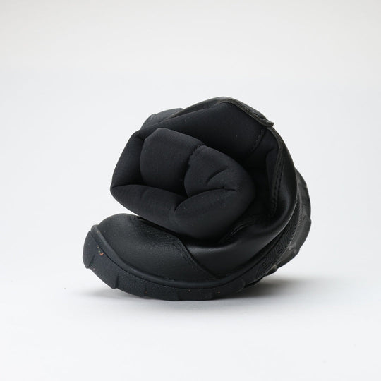 Vaistoa Kinos – lasten korkeavartiset paljasjalkakengät talveen, väri musta. Kuvassa kenkä rullattuna, korostaen ohutta ja joustavaa pohjaa.