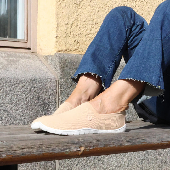 Vaistoa Lempeä 2 barefoot slip-on shoes peach – lifestyle photo, spring outfit, blue jeans sitting on bench