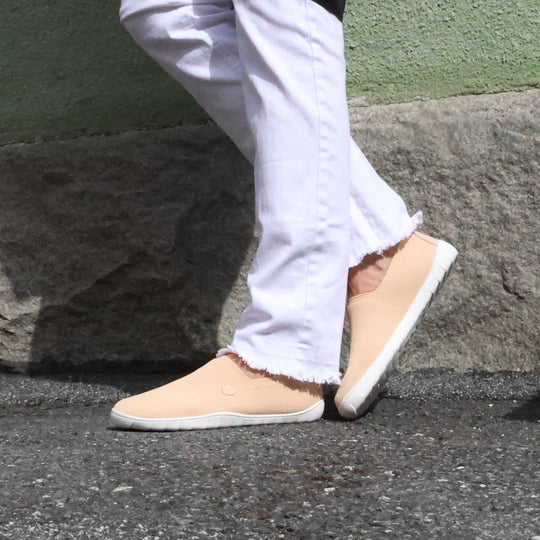 Vaistoa Lempeä 2 barefoot slip-on shoes peach – lifestyle photo, white jeans walking on asphalt