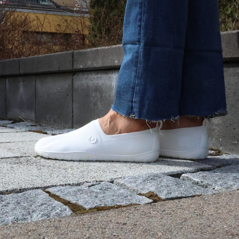Vaistoa Lempeä 2 barefoot slip-on shoes white – lifestyle photo, spring outfit, blue jeans on stone terrace
