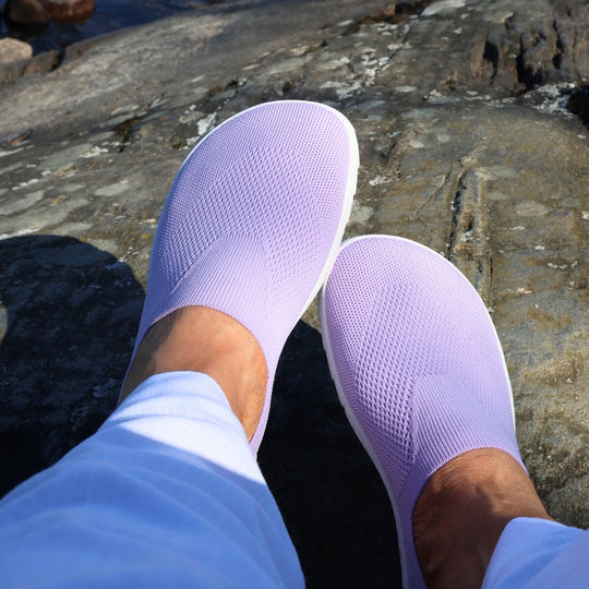 Vaistoa Lempeä 3 slip-on barefoot shoes – lavender shoes worn on feet viewed from above, resting on a rock surface