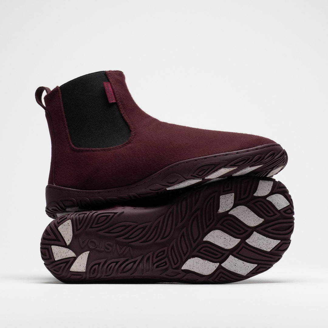 Vaistoa Sulo 2 winter barefoot chelsea boots – one shoe standing on top of the other shoe's outsole, showing the elastic panel of the upper shoe and the Vaistoa logo and grip pads on the outsole below