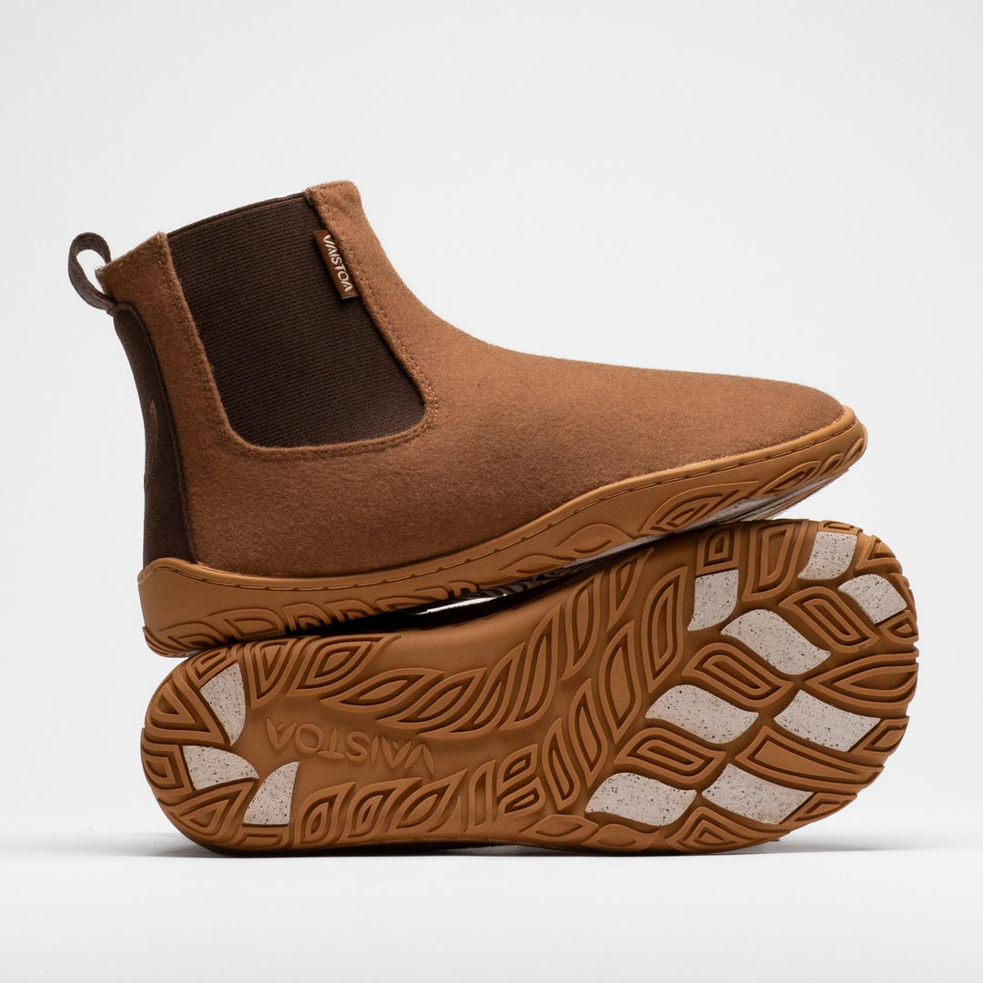Vaistoa Sulo 2 winter barefoot chelsea boots – one shoe standing on top of the other shoe's outsole, showing the elastic panel of the upper shoe and the Vaistoa logo and grip pads on the outsole below