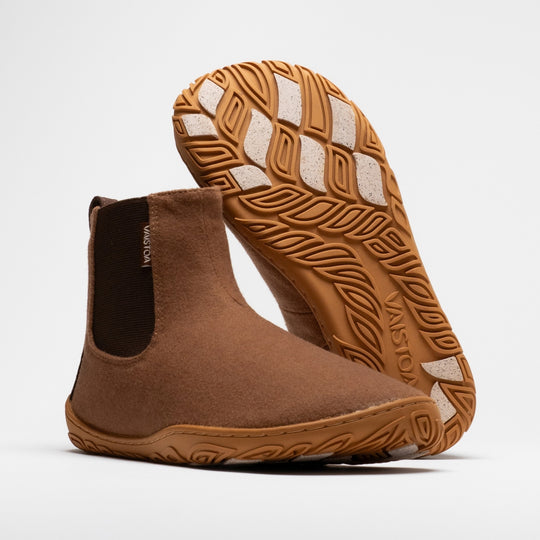 Vaistoa Sulo 2 winter barefoot chelsea boots – pair with one shoe standing with the elastic panel visible and the other leaning behind it with the outsole facing the camera, the Vaistoa logo and grip pads shown large