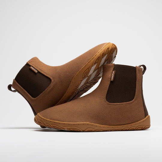 Vaistoa Sulo 2 winter barefoot chelsea boots – pair with one shoe lying on its side behind with the outsole angled upward and the other standing in front, the elastic panels of both visible