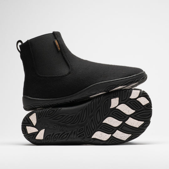 Vaistoa Sulo 2 winter barefoot chelsea boots – one shoe standing on top of the other shoe's outsole, showing the elastic panel of the upper shoe and the Vaistoa logo and grip pads on the outsole below
