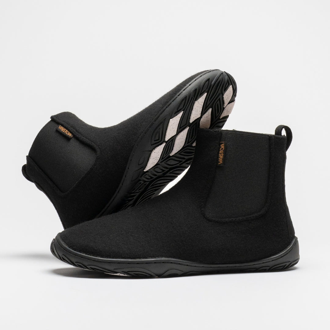 Vaistoa Sulo 2 winter barefoot chelsea boots – pair with one shoe lying on its side behind with the outsole angled upward and the other standing in front, the elastic panels of both visible