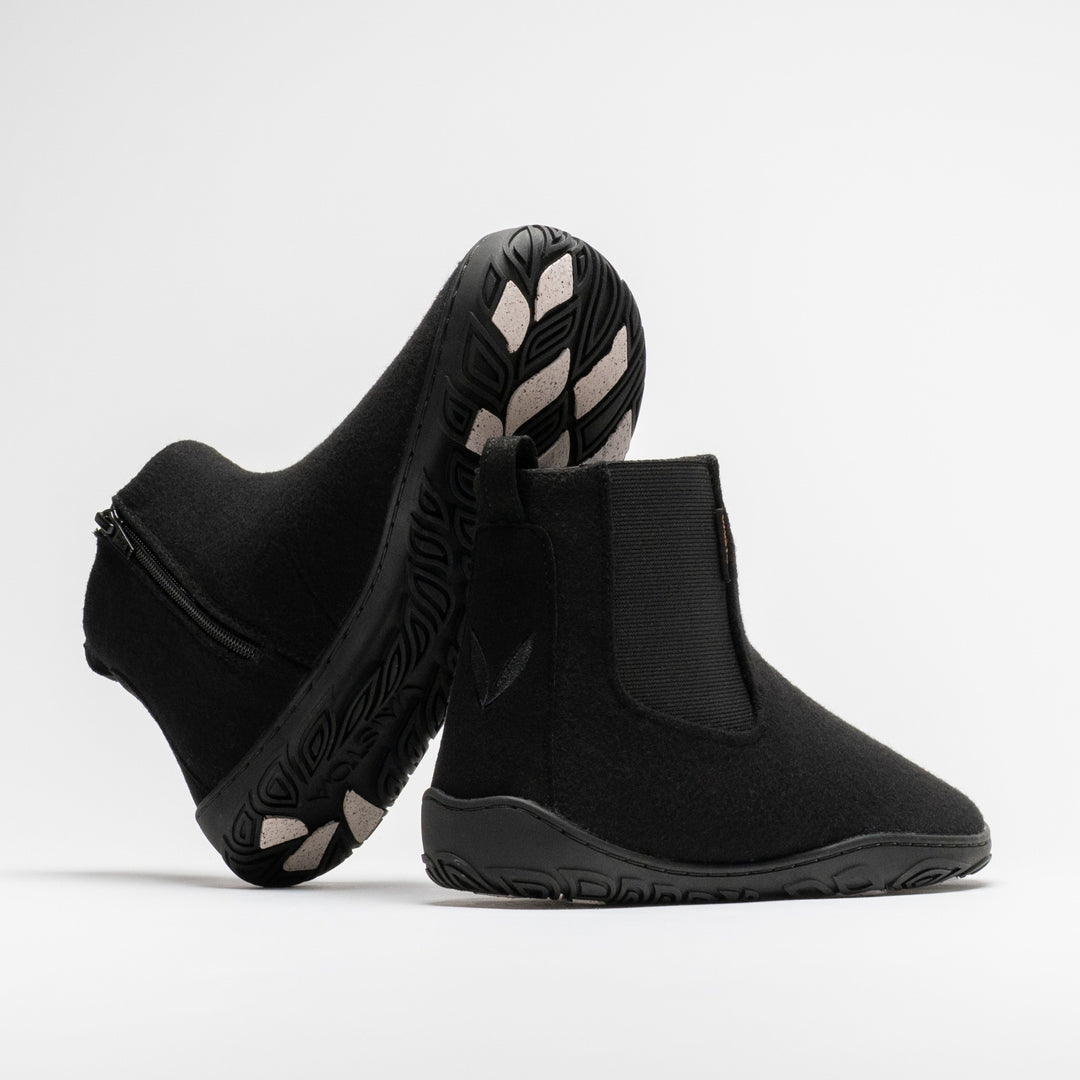 Vaistoa Sulo 2 winter barefoot chelsea boots – pair with one shoe tilted on its side showing the zipper and the grip pads on the outsole and the other standing next to it with the Vaistoa leaf symbol on the heel