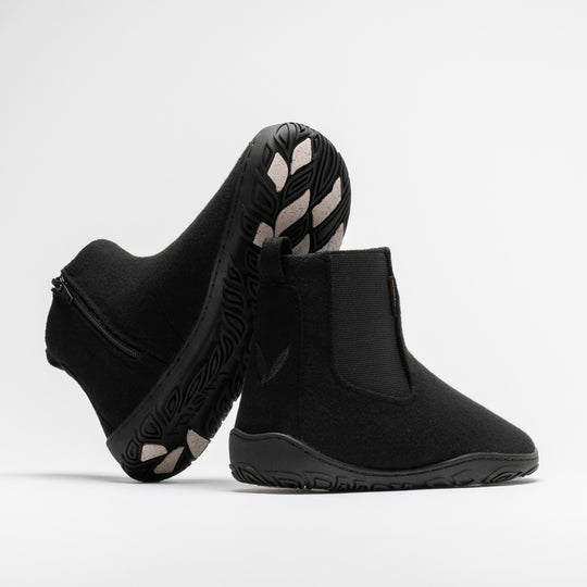 Vaistoa Sulo 2 winter barefoot chelsea boots – pair with one shoe tilted on its side showing the zipper and the grip pads on the outsole and the other standing next to it with the Vaistoa leaf symbol on the heel