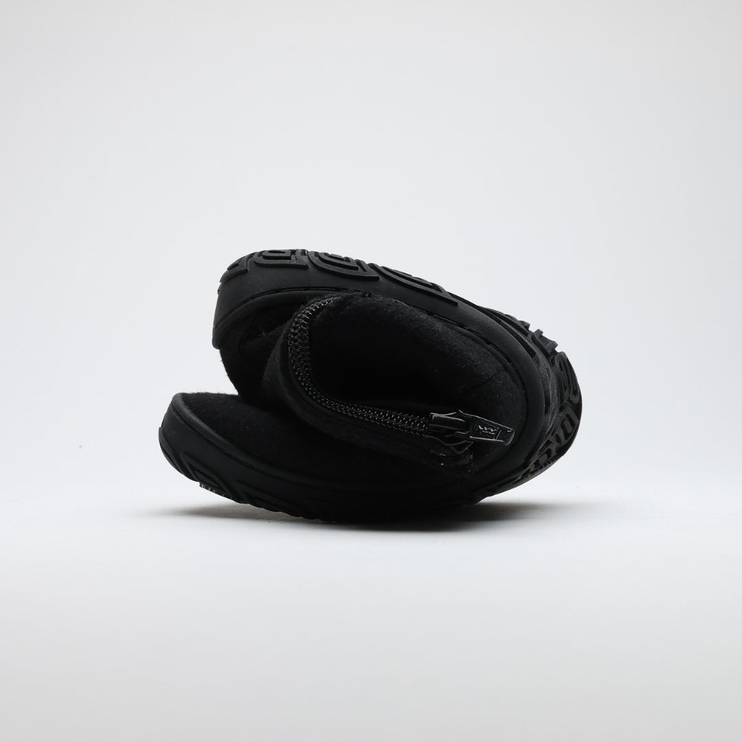 Velvet black barefoot winter felt Chelsea boot folded to demonstrate its thin and flexible sole on a light gray background.