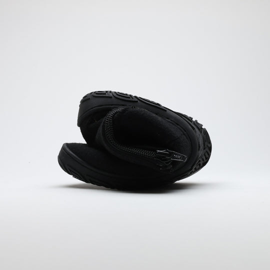 Velvet black barefoot winter felt Chelsea boot folded to demonstrate its thin and flexible sole on a light gray background.