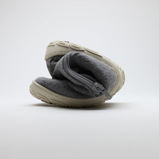 Kuva näyttää helmenharmaan Vaistoa Sulo -huopanilkkurin rullattuna kokoon. Kuvassa korostuu kengän ohut ja joustava pohja, joka mahdollistaa luonnollisen liikkeen ja paljasjalkatuntuman.