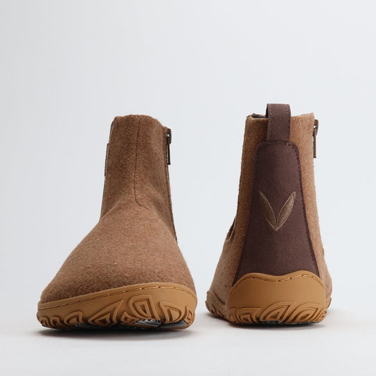 Kuva paahdetun mantelin värisistä Vaistoa Sulo -huopanilkkureista edestä ja takaa. Kuvassa näkyy kenkien leveä varvastila, pehmeä huopapinta sekä takaosassa oleva vetolenkki ja hillitty Vaistoa-logo.