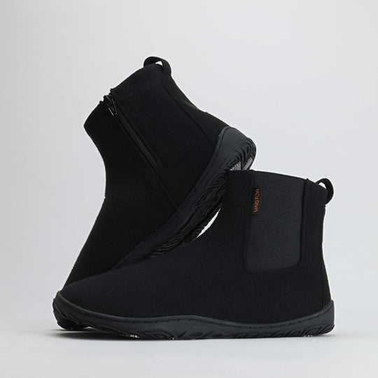 Kaksi samettisen mustaa Vaistoa Sulo -huopanilkkuria seisovat vierekkäin valkoisella taustalla. Toinen kenkä nojaa toisen varteen, paljastaen joustavan Vaistoa Pitoa™ -talvipohjan ja minimalistisen muotoilun. Kuvan oikeassa yläkulmassa näkyy Design from Finland -merkki, joka kertoo kotimaisesta suunnittelusta.