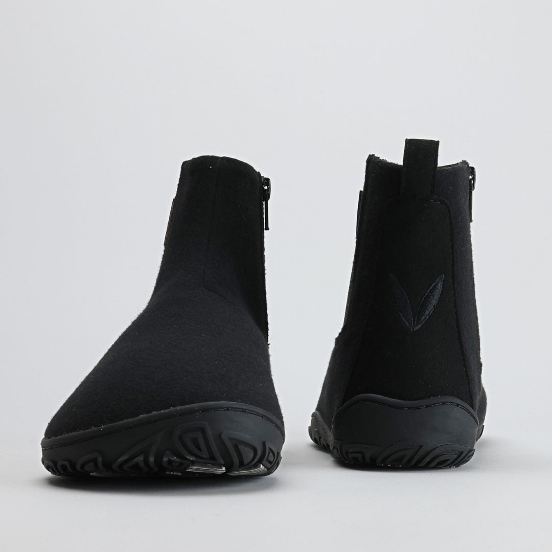 Kuva samettisen mustista Vaistoa Sulo – huopanilkkureista edestä ja takaa. Vasemmassa kengässä näkyy leveä varvastila, oikeassa takana Vaistoa-logon lehtisymboli, joka korostaa minimalistista muotoilua.