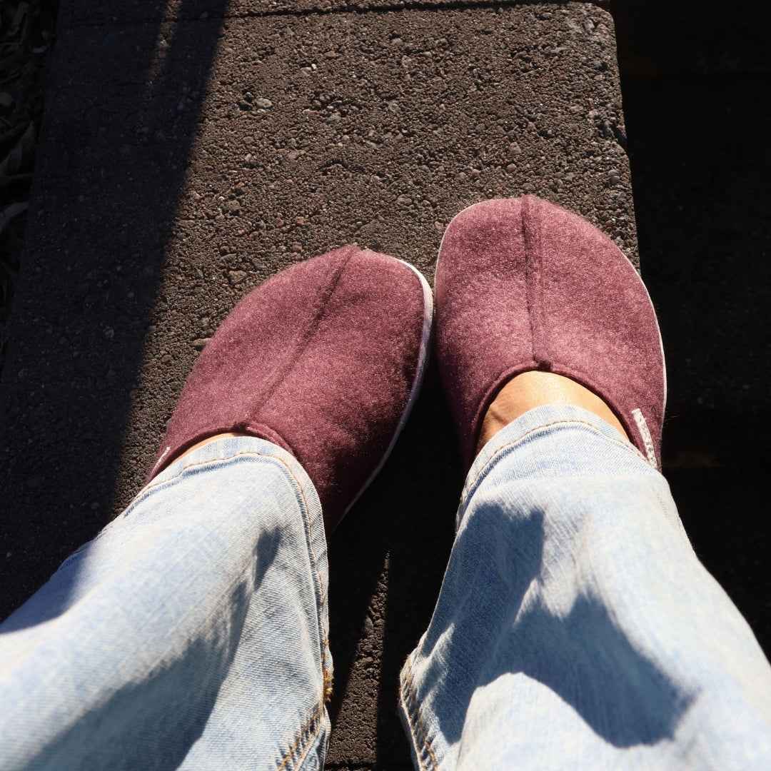 Vaistoa Toive felt barefoot slippers – burgundy felt slippers worn and shown from above, light jeans and strong sunlight on a concrete outdoor step