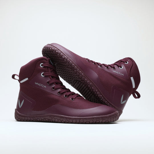 Vaistoa Tuohi 2 barefoot light hiking shoes burgundy – one shoe standing and the other lying on its side resting against its shaft so that the outsole faces the camera broadly and the upper shows from the side